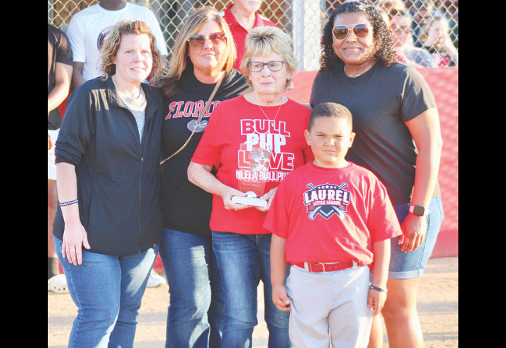 Group of six people posing at a baseball field; a boy in a red Laurel Little League shirt stands front center with five adults behind him.