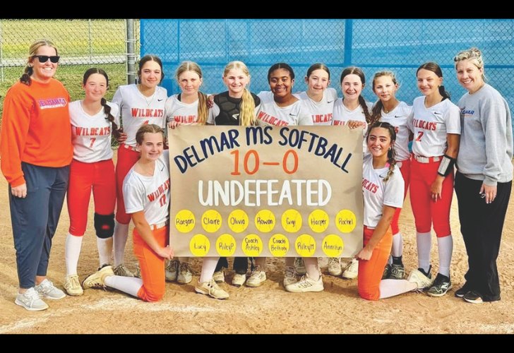 Delmar MS SB L27 Girls softball team posing with a handmade banner reading 'Delmar MS Softball 10-0 Undefeated' after a win. Coaches stand at ends.
