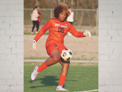 LAU – Mia Robinson Female soccer goalkeeper in orange jersey (number 00) kicking a ball during a game on the field.
