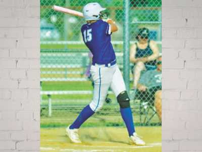 SEA – Emma Short Baseball batter in a purple uniform swinging at a pitch, wearing helmet and knee guard, on a dirt batter's box with a chain-link fence and spectators behind.