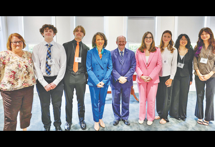 Group of ten professionals in a line indoors, wearing business attire and name badges.