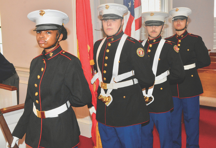 Colors- page 31 Four uniformed Marine cadets stand at attention in a ceremonial room, with flags visible behind them.