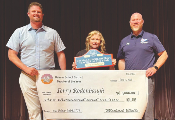 Three adults on a stage hold a large Delmar School District Teacher of the Year check for $2,000; the recipient is Terry Rodenbaugh, flanked by two presenters.