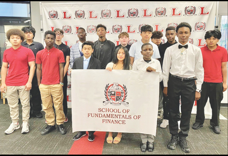 Group of diverse students posing with a banner that reads 'School of Fundamentals of Finance' in front of a backdrop with red L logos.