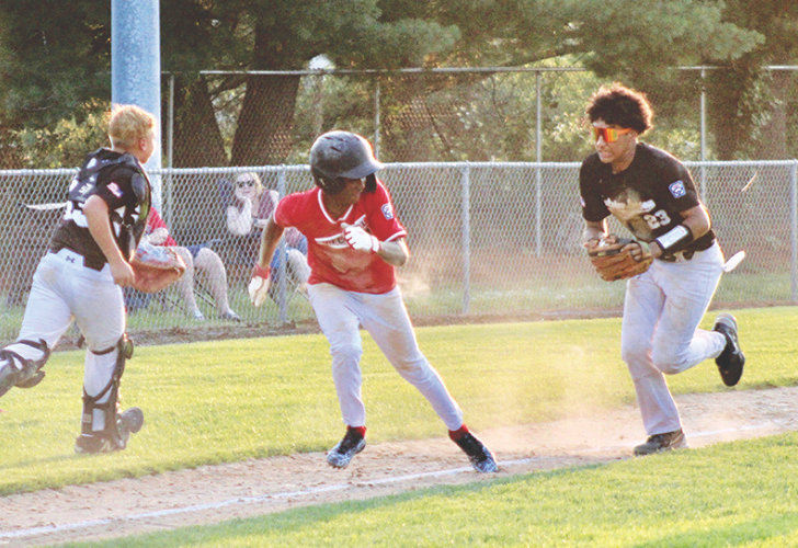 RUNDOWN 39 Youth baseball game: baserunner in red slides into a base as a black-uniform fielder charges after him; catcher watches nearby.