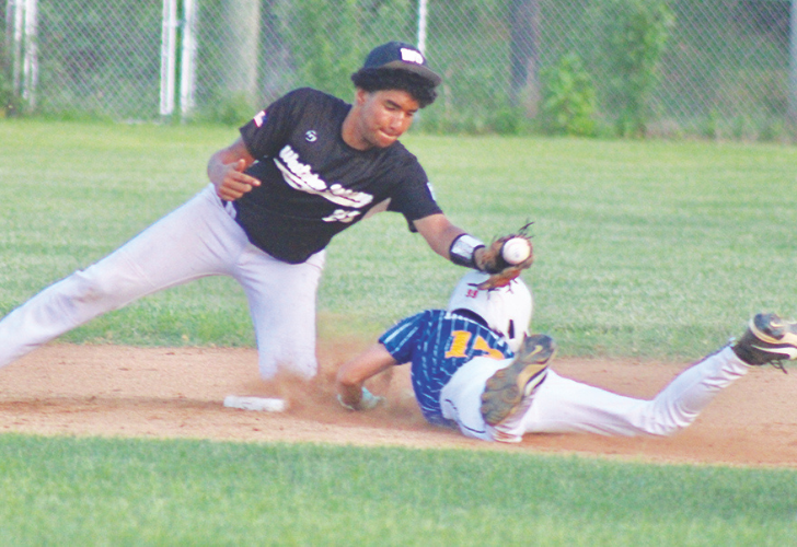 Sabino- Seaford 27 Baseball action: fielder in a black shirt and cap reaches for the ball as a runner slides into a base on a dirt infield.