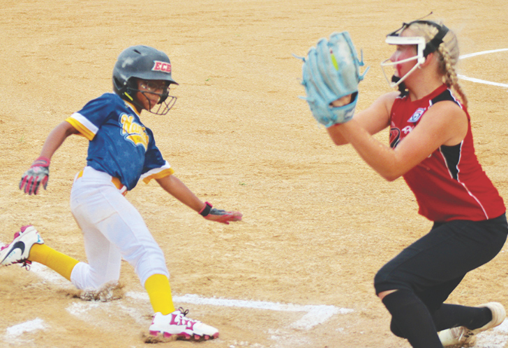 Weatherly- 28 Young softball player in blue and yellow slides into base as a catcher in red reaches with a glove at home plate.